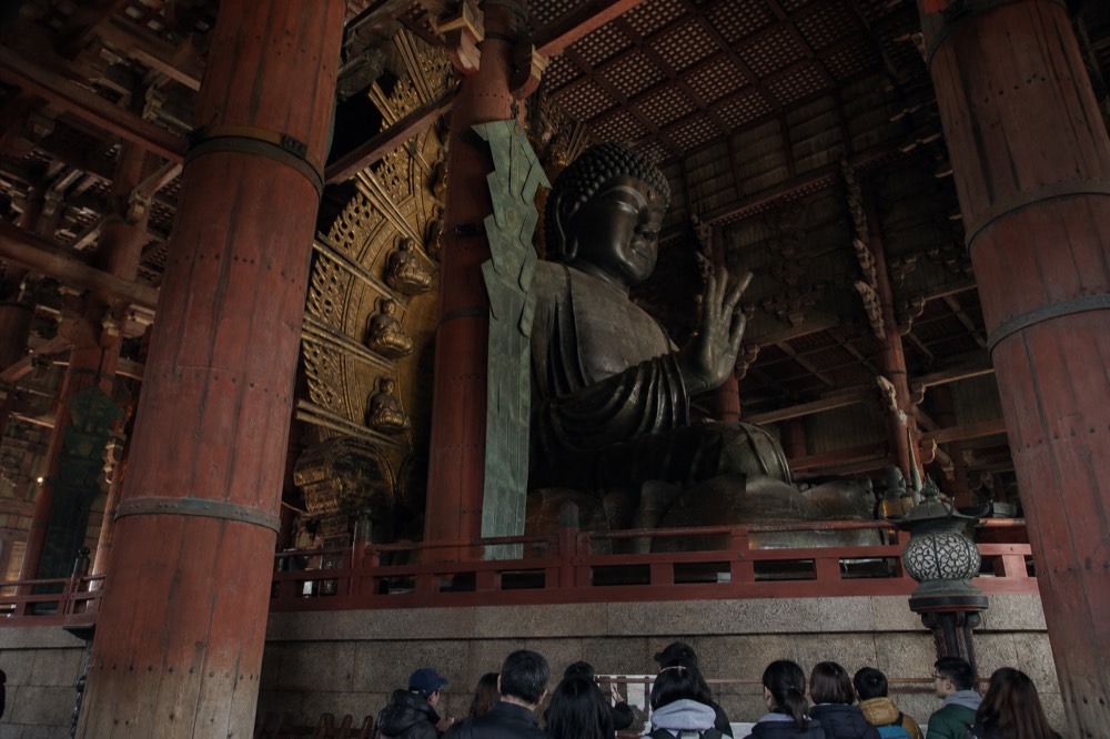 The Great Buddha inside Todai-ji's Daibutsuden hall with visitors for scale
