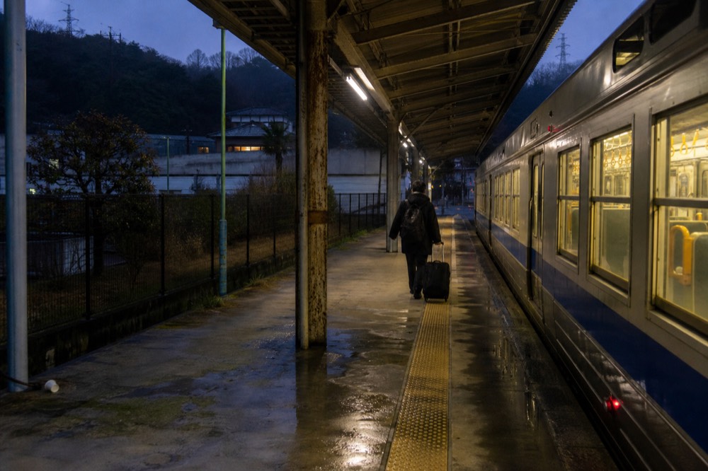 A station platform with a train waiting beside a covered roof structure