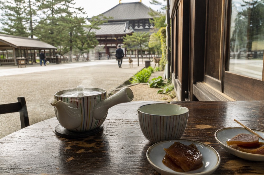 A cafe table set with a pot of green tea and small pickled dishes