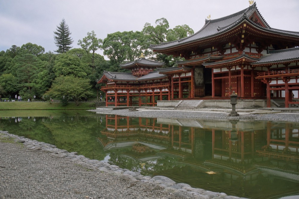 The Byodo-in Phoenix Hall reflected in a calm pond with green trees behind it