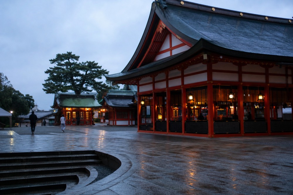 Main shrine hall with worshippers and lantern-lit buildings in early light