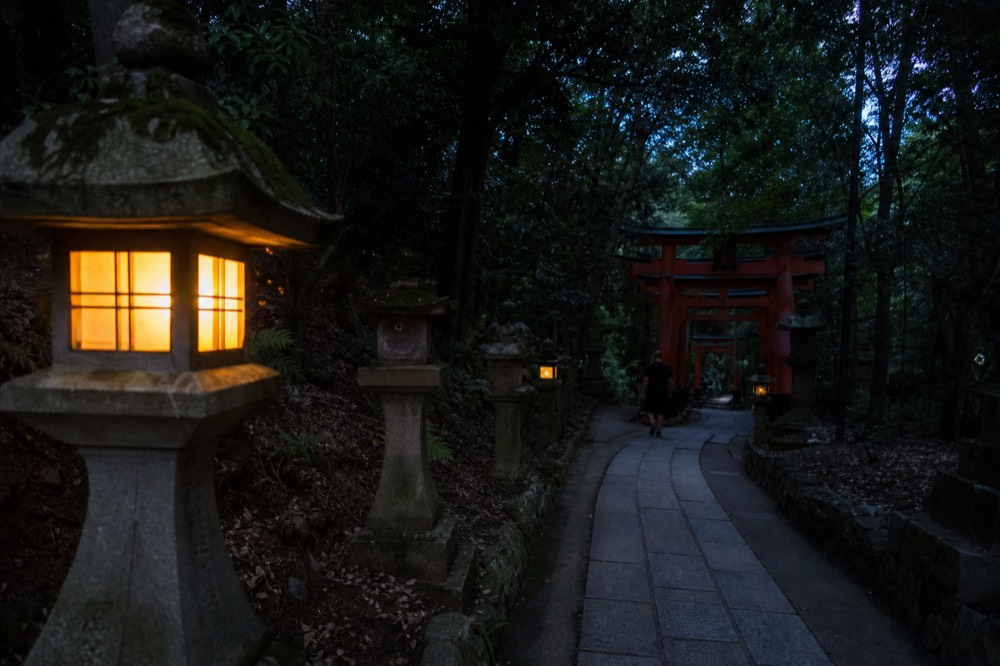 Quiet lantern-lit shrine path in the evening with few visitors