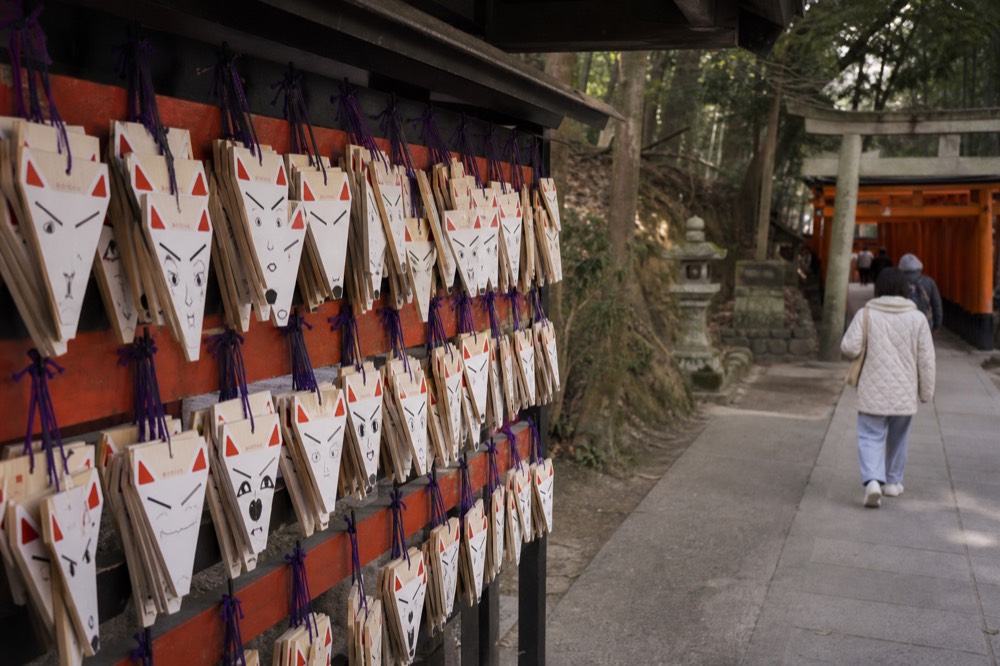 Rows of wooden fox-face wish plaques hanging on a rack