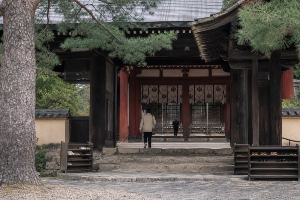 A wooden ticket gate at a temple entrance with paper talismans for sale