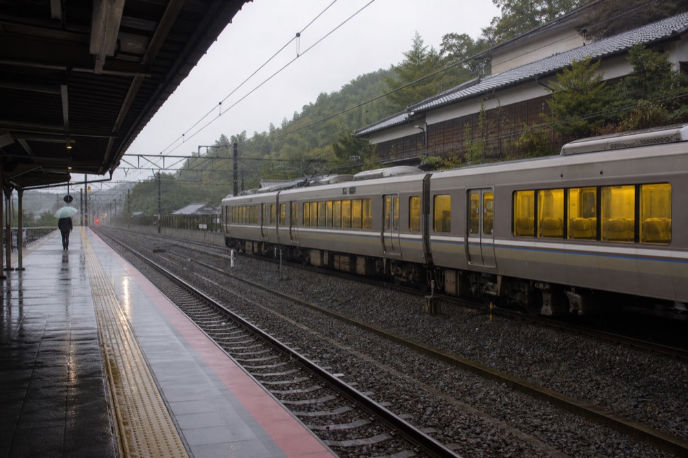 A train platform with a commuter train stopped beside a signboard