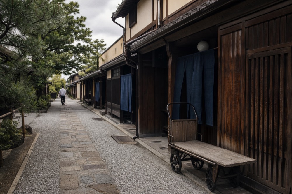 A narrow traditional street with wooden merchant houses and shop banners