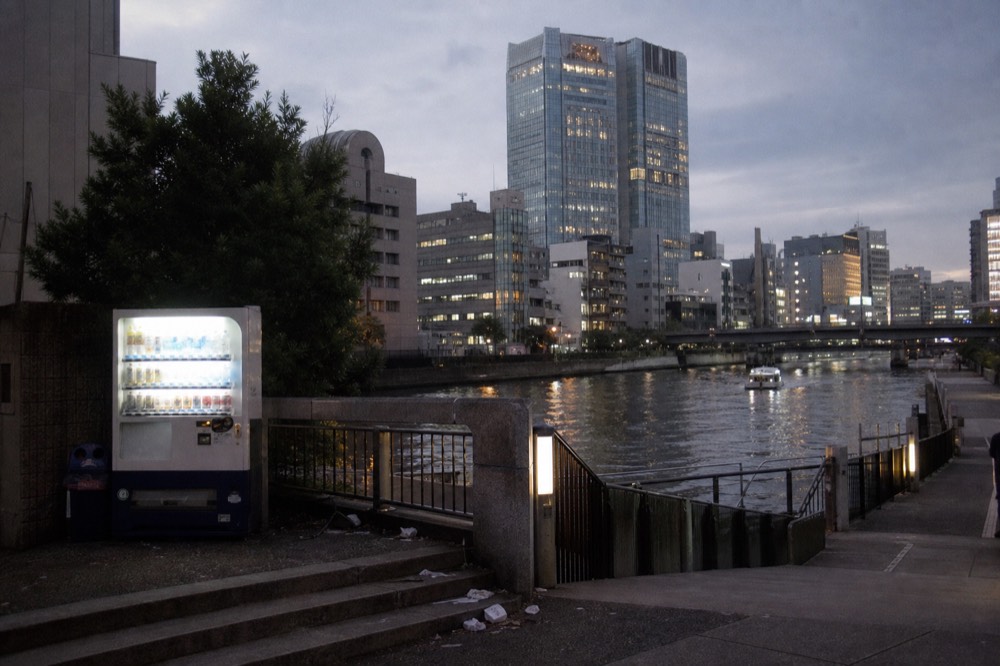 A city skyline of modern towers seen across a river at dusk