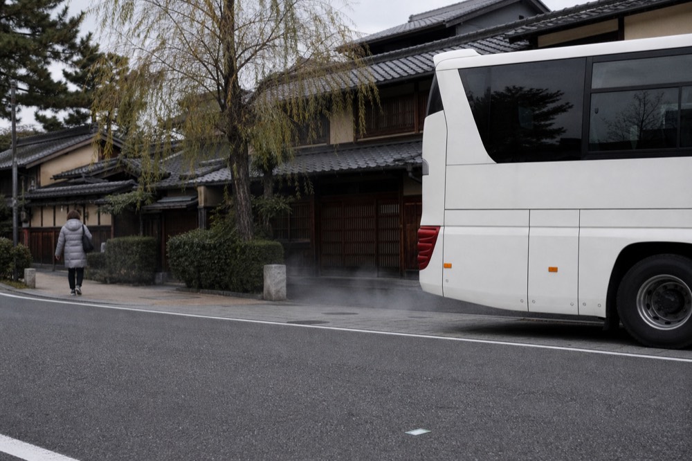 Tour coach parked on a street beside traditional buildings