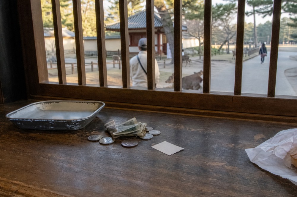 Coins and notes beside a paper ticket on a wooden counter
