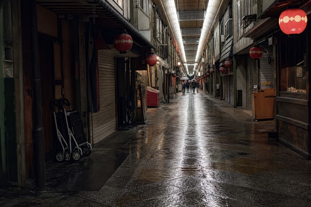 A long covered shopping arcade street with lanterns and shop fronts