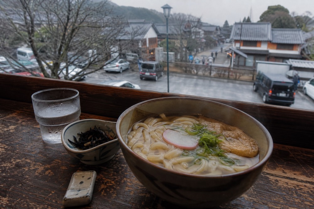 A bowl of noodle soup and small side dishes on a wooden restaurant counter