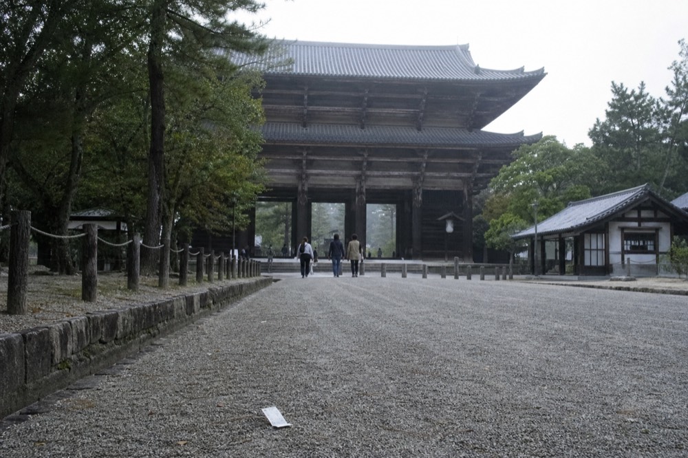 A wide gravel approach leading to a large wooden temple gate