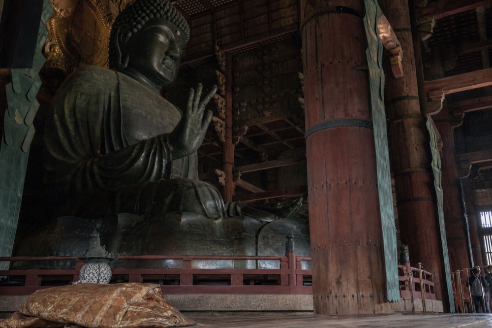 Bronze Buddha statue seated inside a vast wooden hall