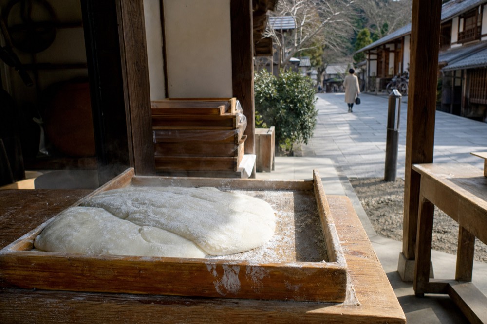 Freshly pounded rice cakes dusted with flour on a wooden tray