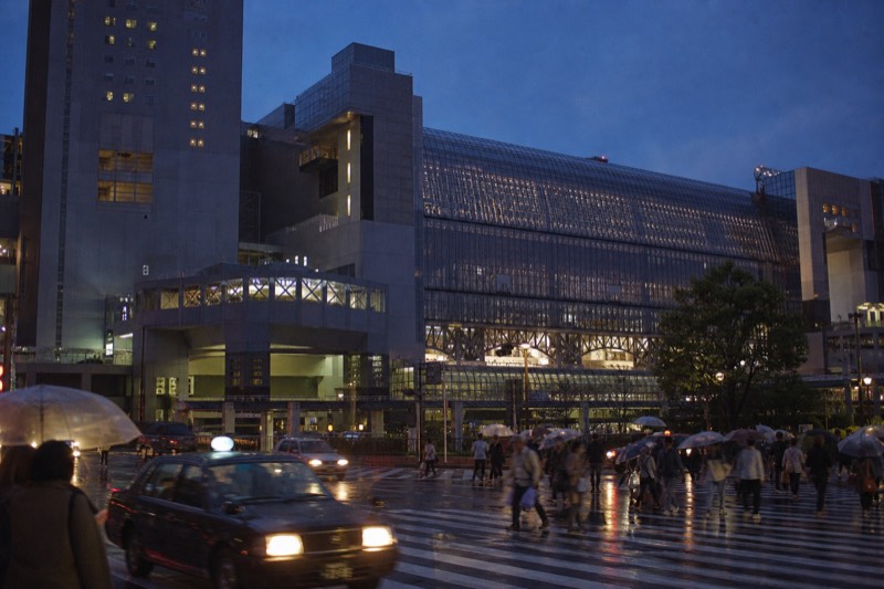 Kyoto Station lit up at night, its glass concourse glowing above the street
