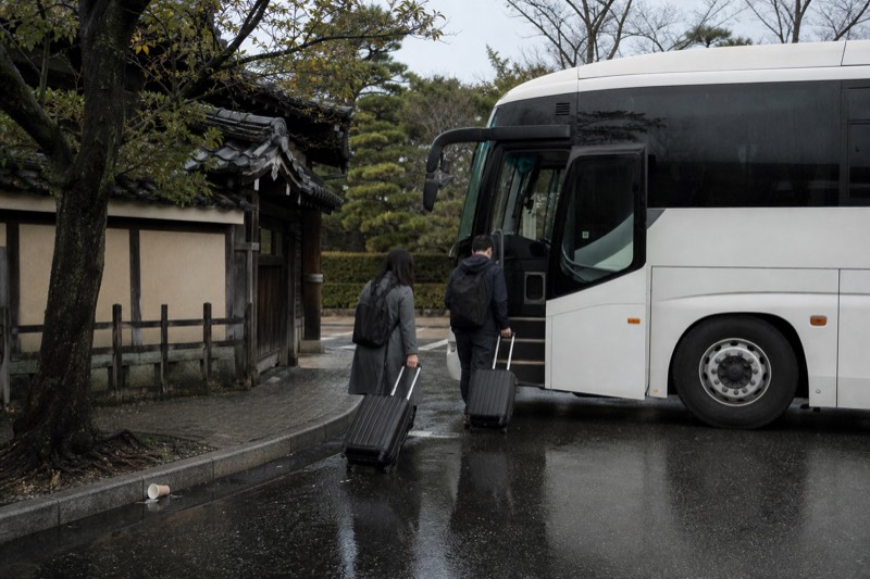 Travellers boarding a tour coach on a morning street in Kyoto